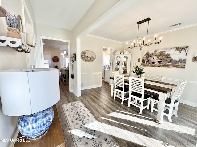 dining room featuring dark wood-type flooring, an inviting chandelier, and crown molding