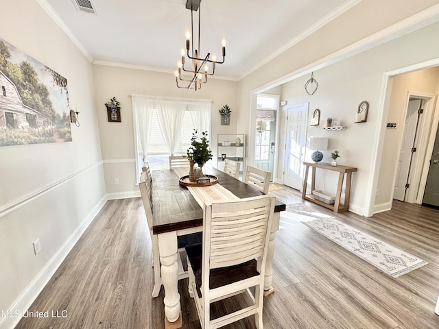 dining area featuring light wood-type flooring, crown molding, and a chandelier