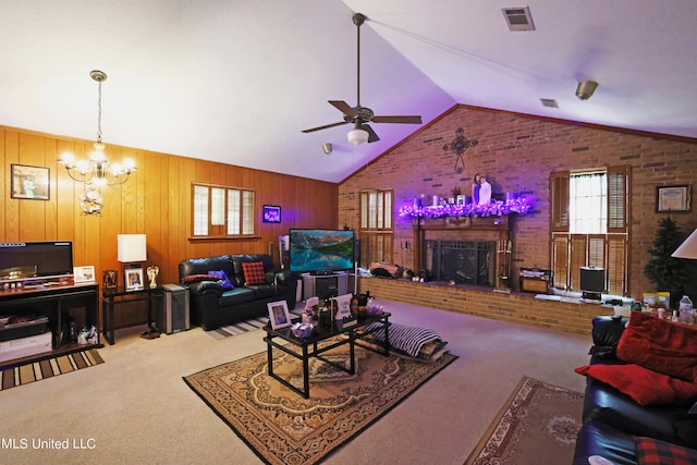 living room featuring wood walls, carpet, a brick fireplace, and ceiling fan with notable chandelier