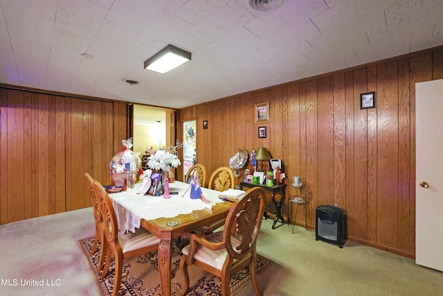 dining space featuring wooden walls and light colored carpet