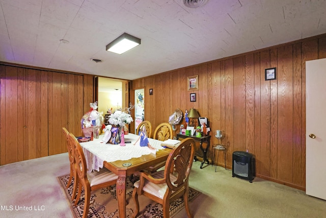 dining room featuring visible vents, wooden walls, and light carpet