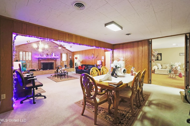 dining space featuring light carpet, wood walls, and a brick fireplace