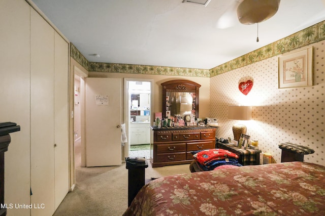 carpeted bedroom with ensuite bathroom and ceiling fan