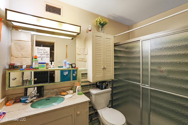 bathroom featuring vanity, toilet, and a shower with door