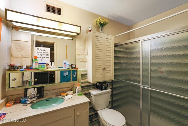 bathroom featuring visible vents, decorative backsplash, vanity, toilet, and a stall shower