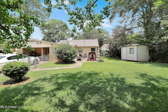 view of yard with a storage shed, fence, an outbuilding, and an attached carport