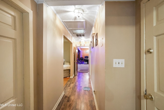 hallway featuring crown molding, hardwood / wood-style flooring, and a textured ceiling