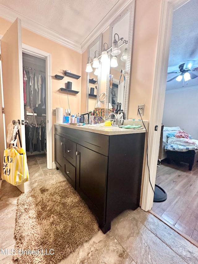 bathroom featuring a textured ceiling, ceiling fan, crown molding, and vanity