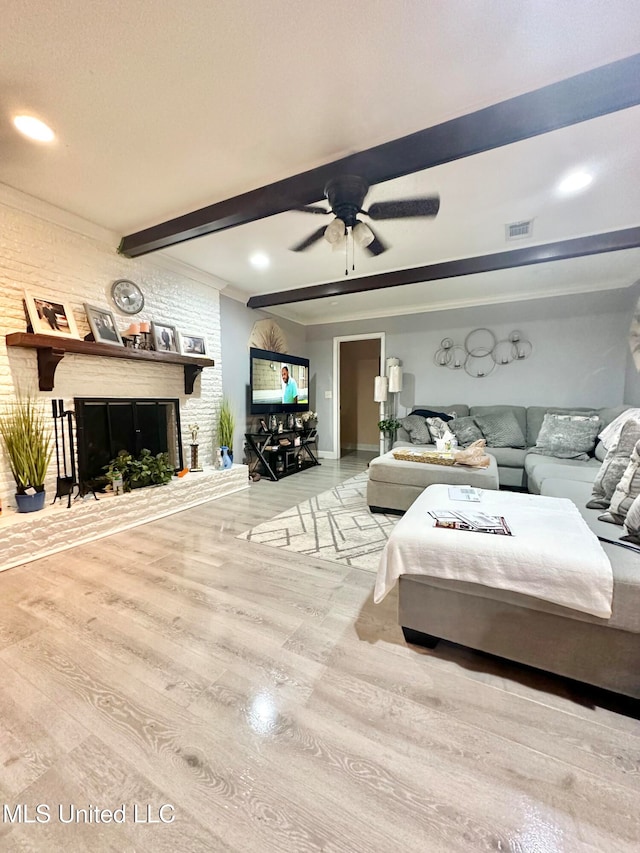 bedroom featuring beamed ceiling, ceiling fan, light hardwood / wood-style floors, and a fireplace