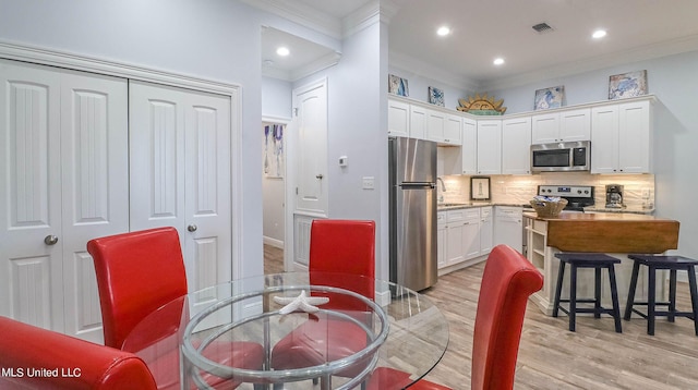 dining area featuring ornamental molding, sink, and light wood-type flooring