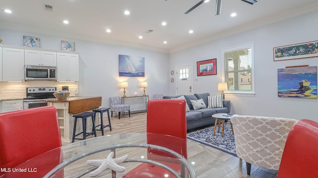 living room featuring crown molding, light hardwood / wood-style floors, and ceiling fan