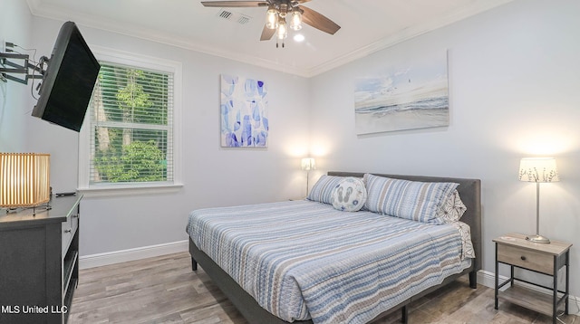 bedroom with ornamental molding, hardwood / wood-style flooring, and ceiling fan