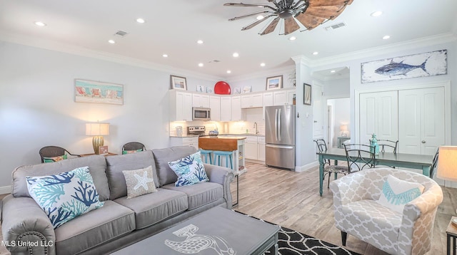 living room featuring light hardwood / wood-style floors, ornamental molding, and ceiling fan