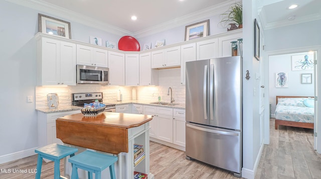 kitchen featuring sink, appliances with stainless steel finishes, light wood-type flooring, and white cabinets