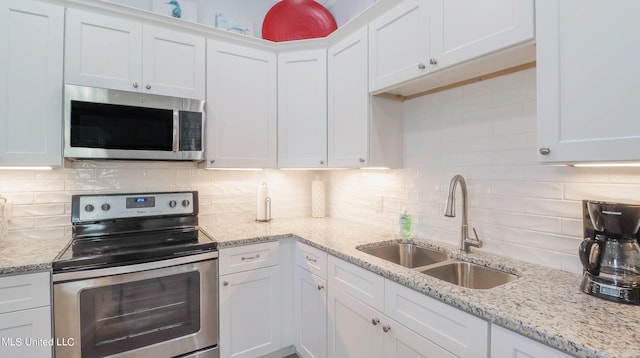 kitchen with white cabinetry, stainless steel appliances, decorative backsplash, and sink