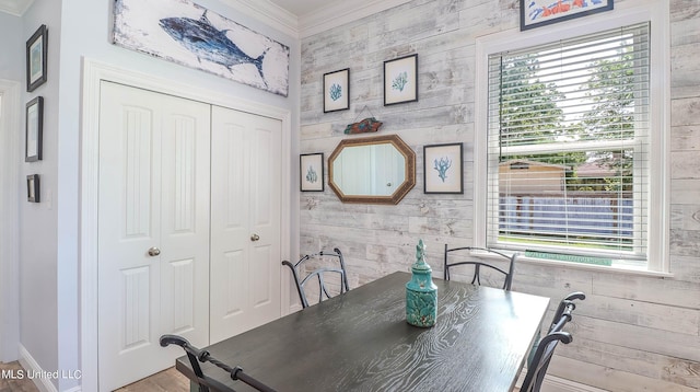 dining area with wooden walls, ornamental molding, and plenty of natural light