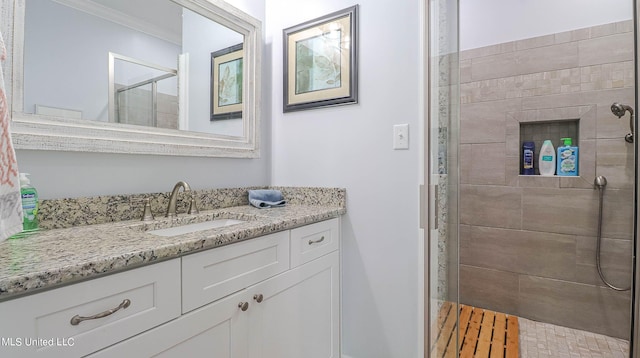 bathroom featuring vanity, ornamental molding, and a tile shower