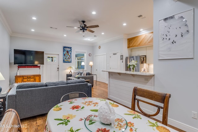 dining space featuring crown molding, light hardwood / wood-style flooring, and ceiling fan