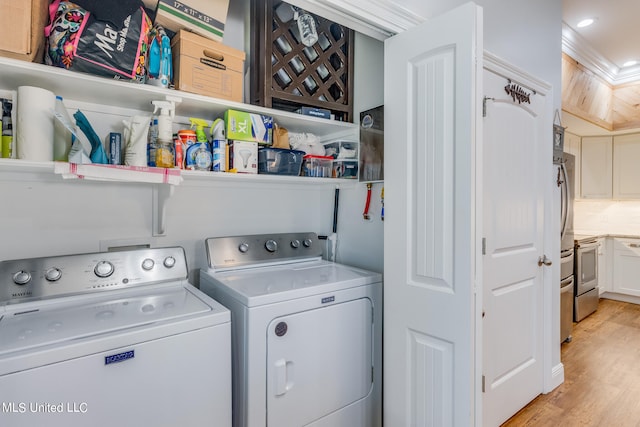 laundry area with washing machine and clothes dryer and light hardwood / wood-style floors