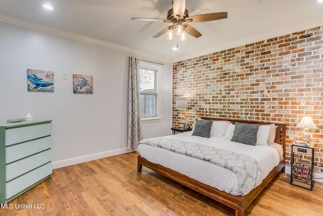 bedroom featuring ornamental molding, brick wall, light wood-type flooring, and ceiling fan