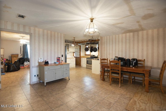 900 Old Benton Rd, Yazoo City, MS 39194 - kitchen with wallpapered walls, stainless steel gas range, wood counters, decorative light fixtures, and a chandelier