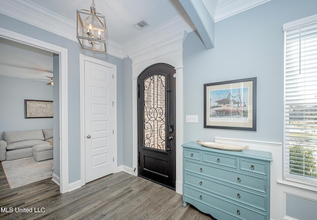 foyer entrance featuring dark wood-type flooring, visible vents, crown molding, and a notable chandelier