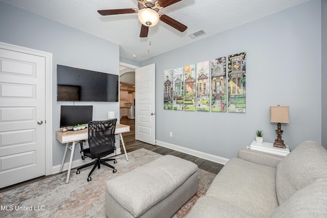 office space with visible vents, a textured ceiling, baseboards, and wood finished floors