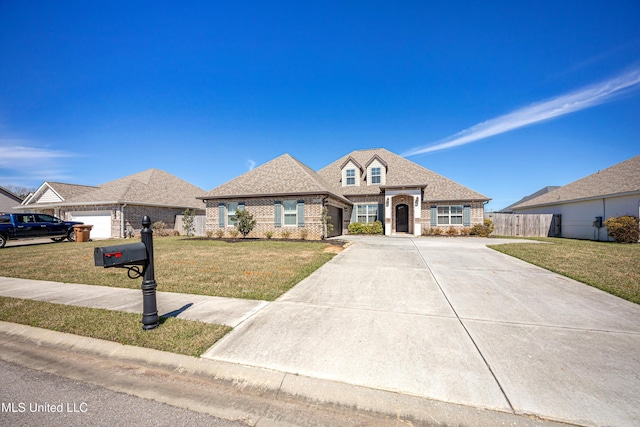 french provincial home featuring a shingled roof, concrete driveway, fence, a front yard, and brick siding