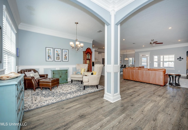 living area featuring crown molding, ornate columns, and wood finished floors