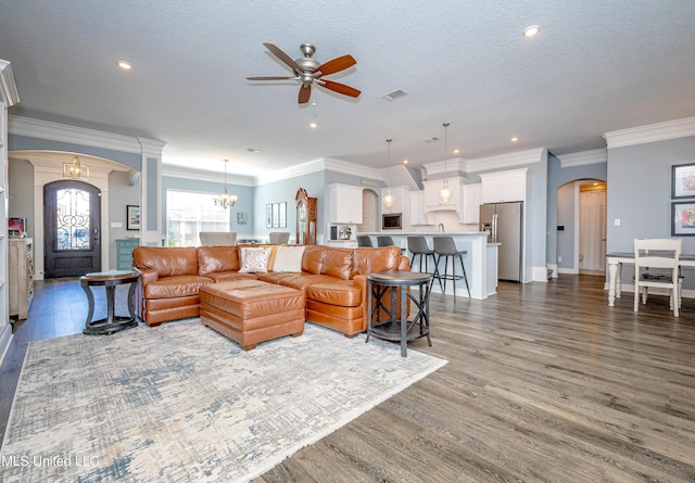 living room featuring arched walkways, a textured ceiling, wood finished floors, and visible vents