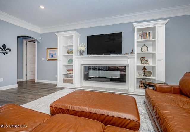 living room with arched walkways, crown molding, a glass covered fireplace, wood finished floors, and baseboards