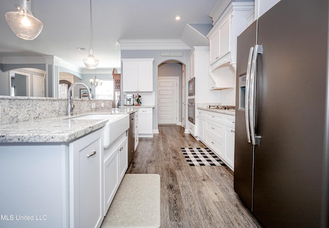 kitchen with wood finished floors, stainless steel appliances, crown molding, white cabinetry, and a sink