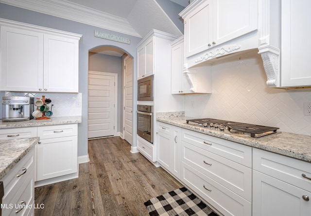 kitchen with stainless steel appliances, arched walkways, white cabinetry, and crown molding