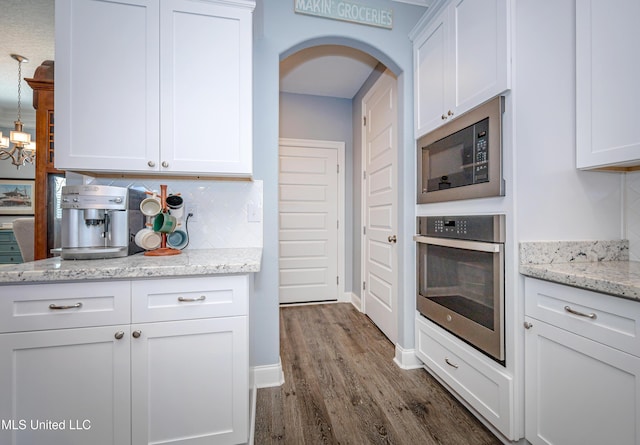 kitchen featuring white cabinets, built in microwave, arched walkways, and oven