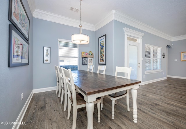 dining space featuring visible vents, arched walkways, dark wood-style flooring, and ornamental molding