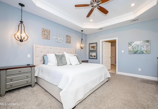 bedroom with visible vents, baseboards, ornamental molding, a tray ceiling, and carpet