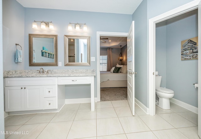 ensuite bathroom featuring toilet, vanity, baseboards, tile patterned floors, and ensuite bath