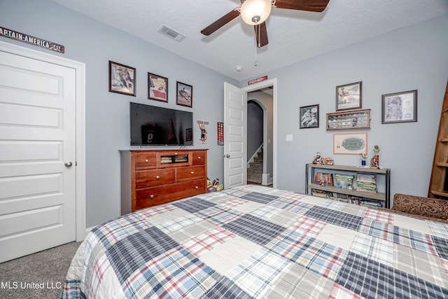 bedroom with carpet floors, visible vents, arched walkways, and a textured ceiling