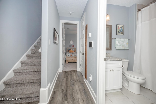 interior space featuring stairs, a textured ceiling, and baseboards