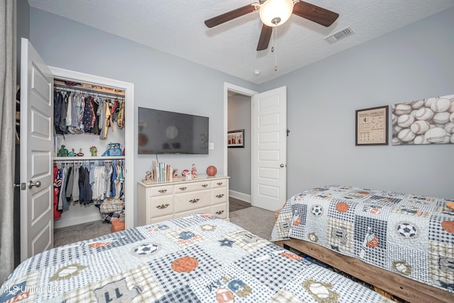 bedroom with visible vents, a ceiling fan, a textured ceiling, carpet floors, and a closet