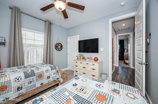 bedroom featuring a textured ceiling, ceiling fan, visible vents, and baseboards