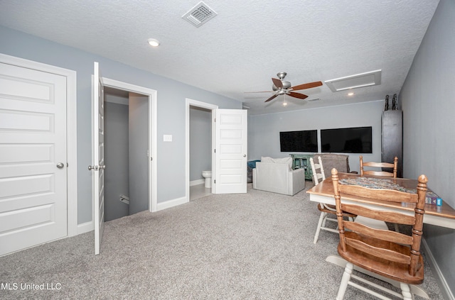 office area with a textured ceiling, ceiling fan, carpet floors, visible vents, and attic access