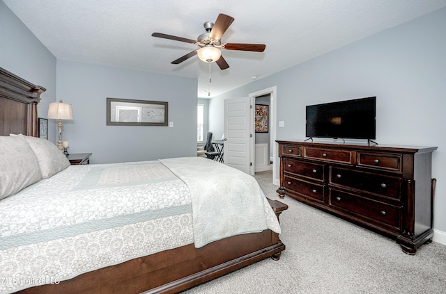 bedroom with light carpet, a textured ceiling, a ceiling fan, and baseboards