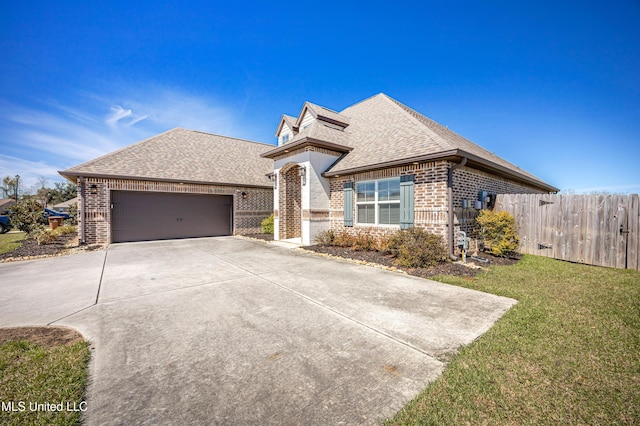 view of front of house featuring brick siding, roof with shingles, an attached garage, fence, and a front lawn