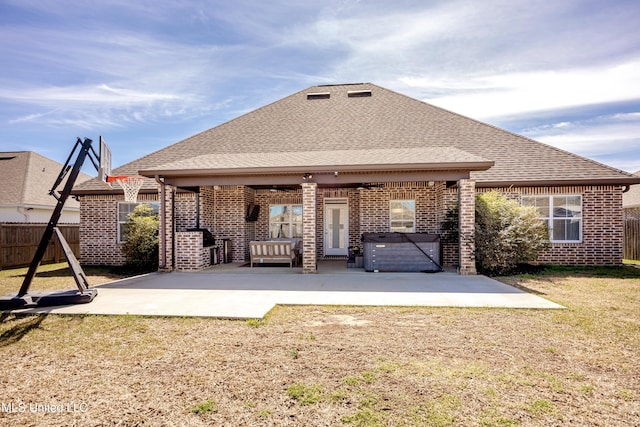 back of house with a patio, brick siding, a shingled roof, fence, and a hot tub