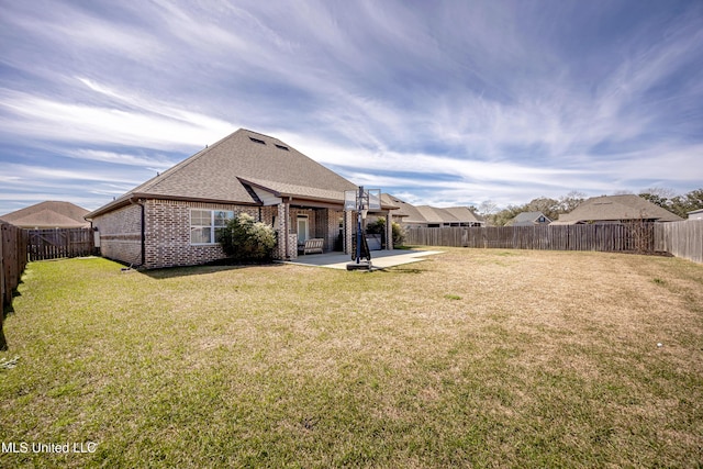 back of property with a patio, a fenced backyard, brick siding, a yard, and roof with shingles