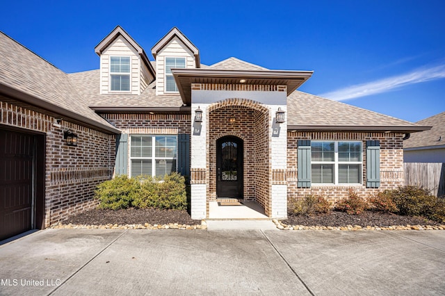 view of front of house featuring brick siding and roof with shingles