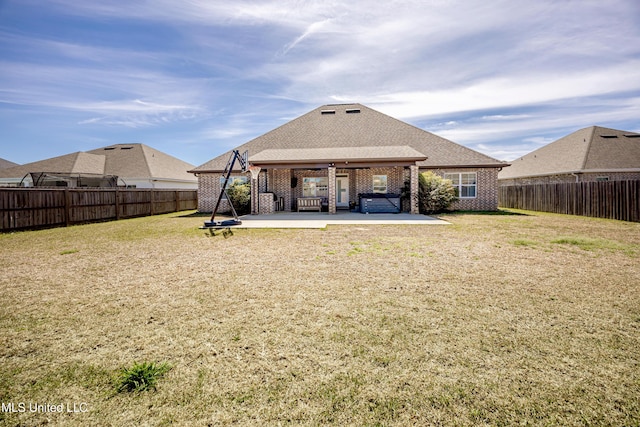 back of house with a yard, brick siding, a patio area, and a fenced backyard