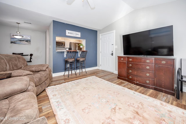 living room with ceiling fan, light hardwood / wood-style floors, and lofted ceiling