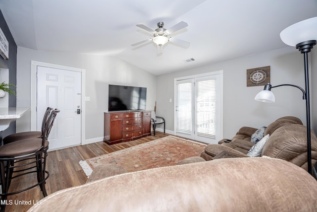 living room with ceiling fan, wood-type flooring, and vaulted ceiling